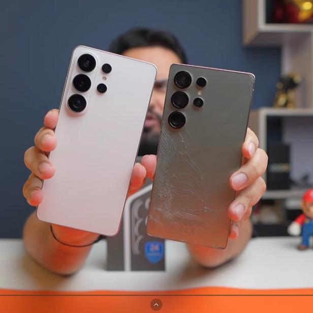 Ein Mann hält 2 Smartphones in die Kamera, eines ist weiß, das andere grau