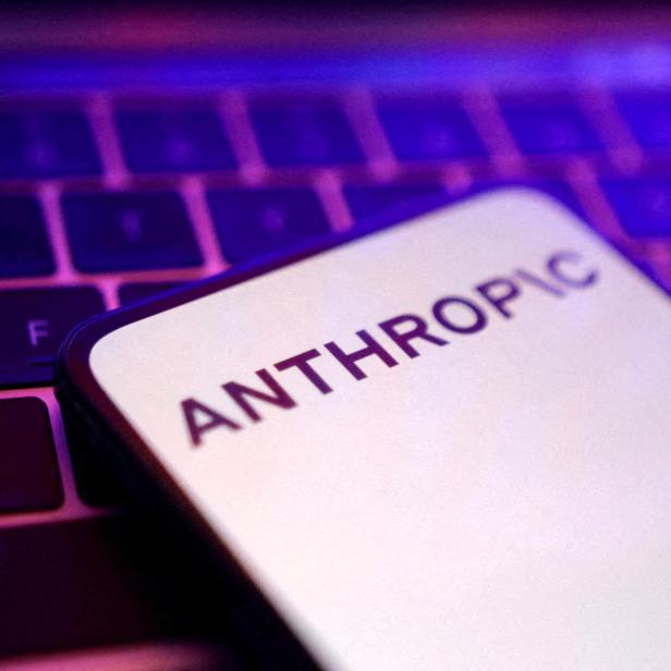Ein Smartphone mit dem Schriftzug „ANTHROPIC“ liegt auf einer beleuchteten Tastatur.