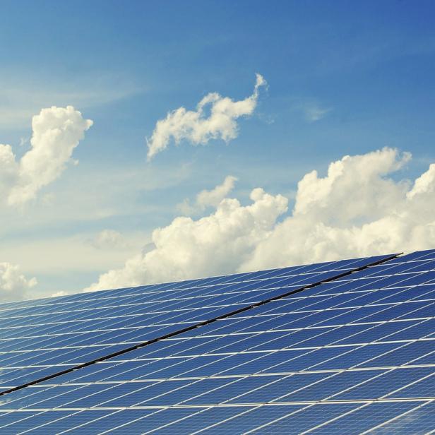 Solarpanels vor einem blauen Himmel mit weißen Wolken.