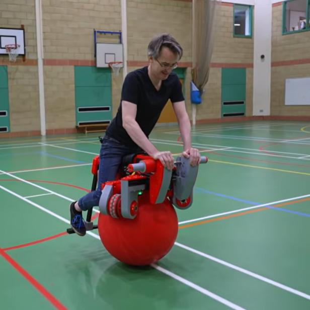 Ein Mann fährt mit einem Gymnastikball-E-Bike durch eine Turnhalle