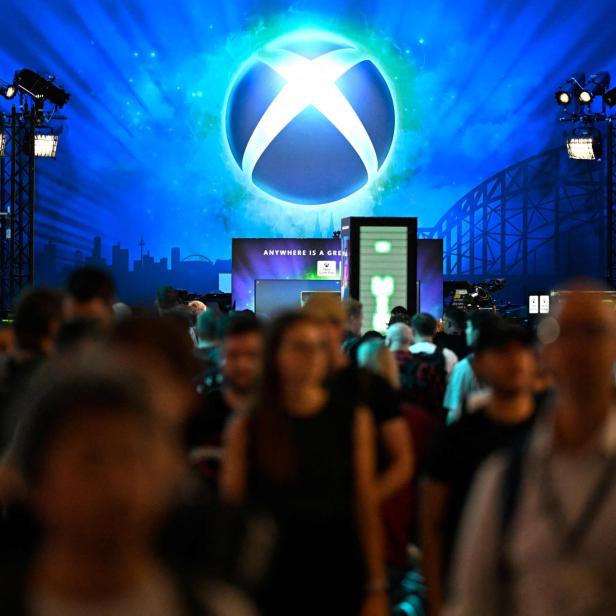 Eine Menschenmenge steht vor einer großen, blau beleuchteten Xbox-Bühne auf einer Messe.