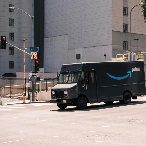Ein Amazon-Prime-Lieferwagen fährt durch eine leere Straßenkreuzung in der Stadt.