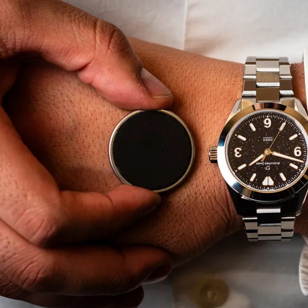 Das münzgroße Gerät neben einer klassischen Uhr.
