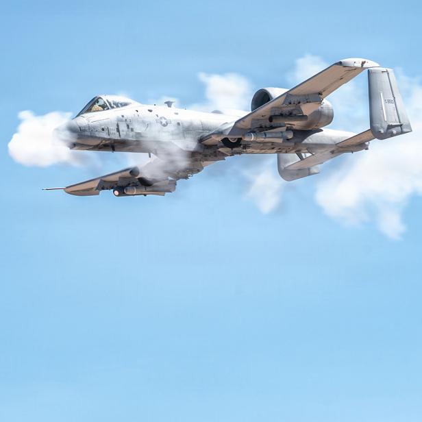 Kampfflugzeug fliegt am Himmel und schießt mit der Bordkanone