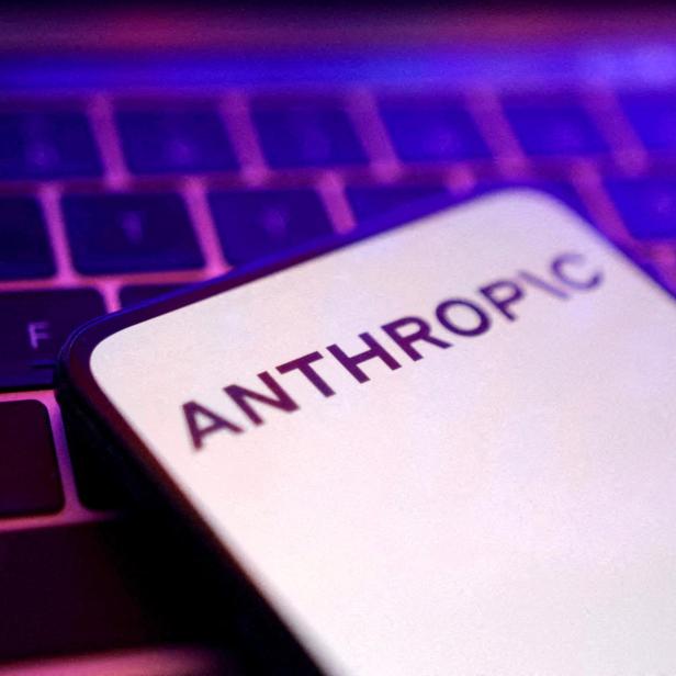 Auf einem Smartphone-Bildschirm steht „ANTHROPIC“, das Gerät liegt auf einer beleuchteten Tastatur.