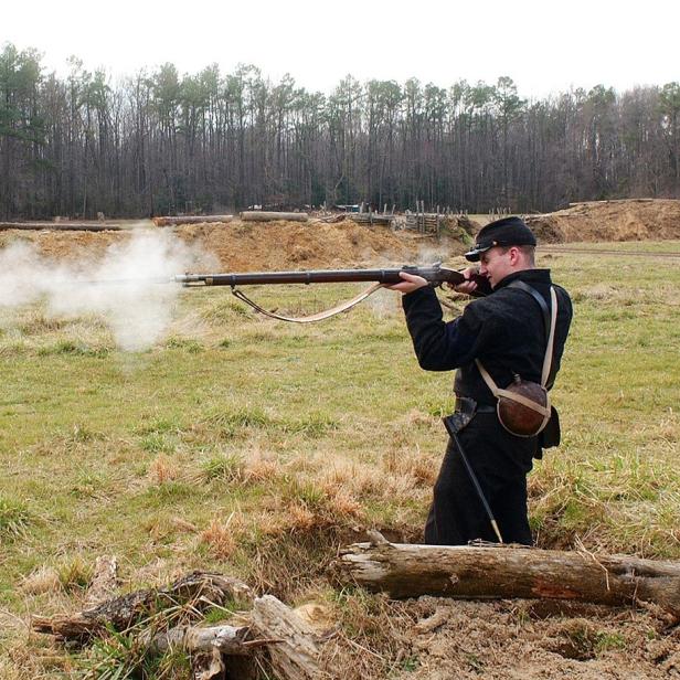 Soldat feuert auf Wiese mit Muskete.