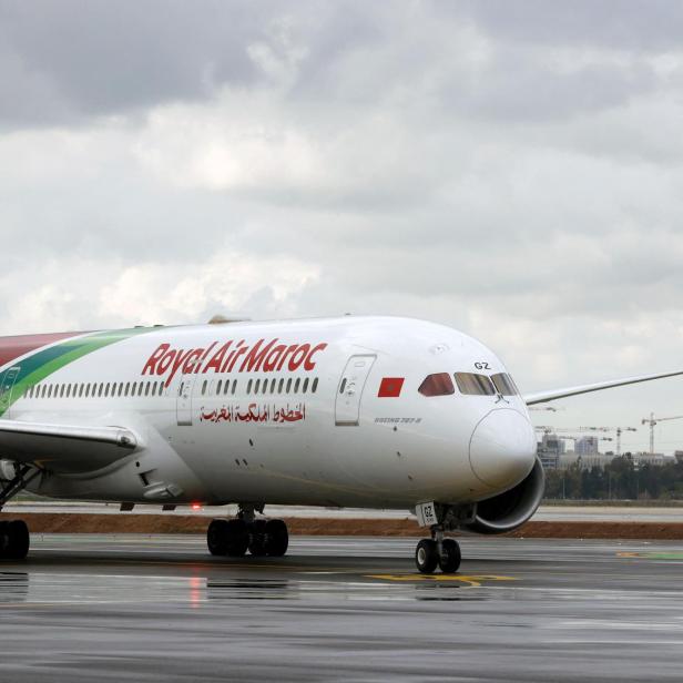 Ein Passagierflugzeug der Royal Air Maroc rollt auf einer nassen Landebahn bei bewölktem Himmel.