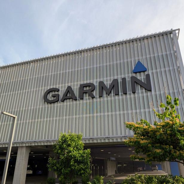 Garmin-Logo an der Fassade eines modernen Gebäudes mit Bäumen im Vordergrund.