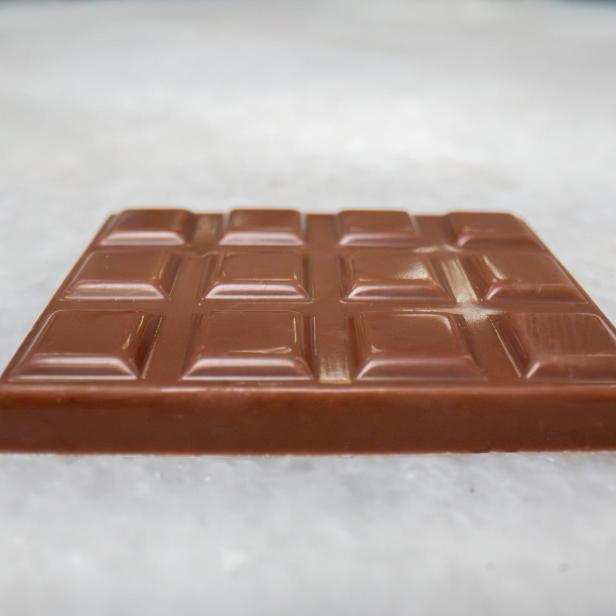 Eine Tafel Milchschokolade von Celleste Bio, hergestellt mit im Labor gezüchteter Kakaobutter, liegt auf einer hellen Oberfläche.