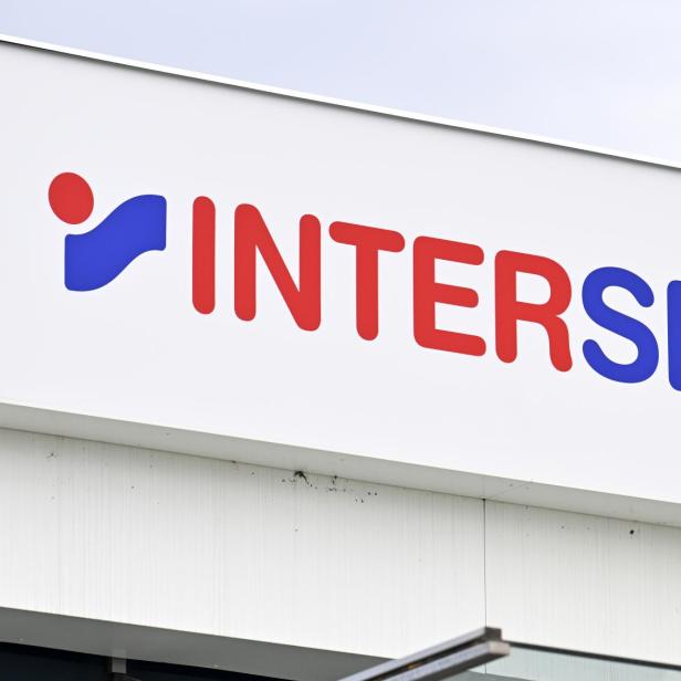 Ein Schild mit dem Schriftzug „INTERSPORT“ in roten und blauen Buchstaben sowie einem blauen und roten Logo.