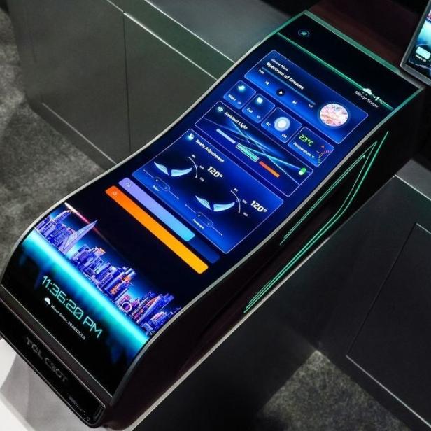 Großer, gebogener Touchscreen in einer Autoarmlehne mit farbigen Anzeigen und Bedienelementen.