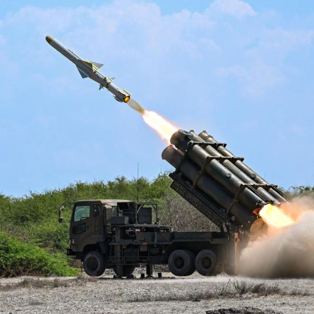 Ein Militärfahrzeug feuert eine Rakete in einer staubigen Landschaft bei Tageslicht ab.