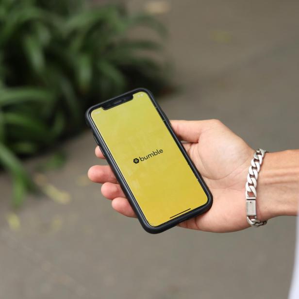 Bumble App auf Handy das in einer Hand liegt