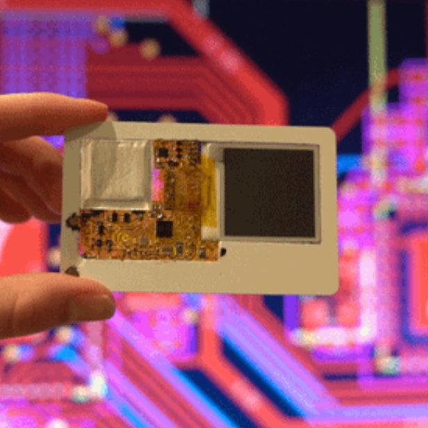 Eine Hand hält einen dünnen Mini-Computer im Kreditkartenformat vor einem bunten Schaltplan.
