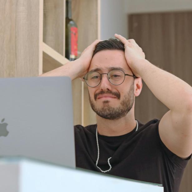 Mann mit verzweifeltem Gesichtsausdruck sitzt vor Mac.