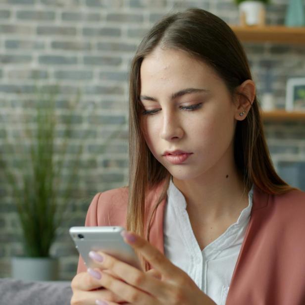 eine Frau schaut bestürzt auf ihr Handy