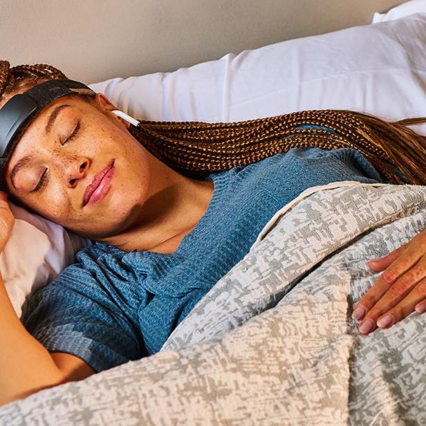 Eine Frau liegt entspannt im Bett und trägt das Muse Athena S Stirnband, das zur Messung von Gehirnwellen während des Schlafs genutzt wird.