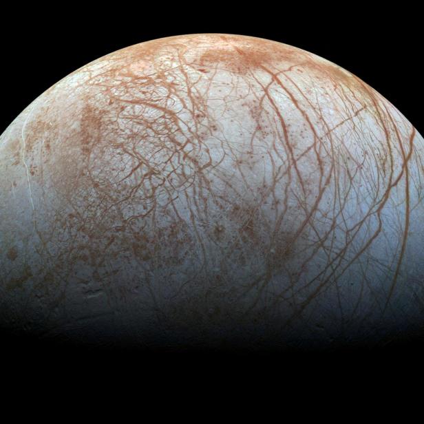 Der Jupitermond Europa zeigt eine eisige Oberfläche mit rötlichen Rissen und Strukturen.