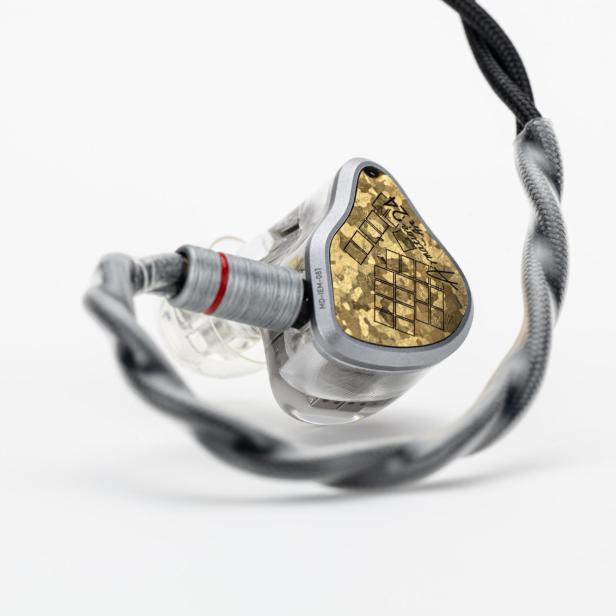 Nahaufnahme eines hochwertigen In-Ear-Kopfhörers mit goldfarbener Abdeckung und geflochtenem Kabel.