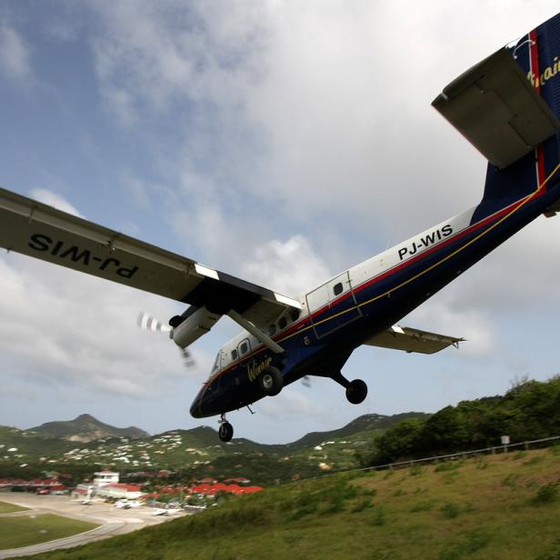 Flugzeug fliegt im Landeanflug knapp über eine Straße am Saint-Barthélemy-Flughafen.