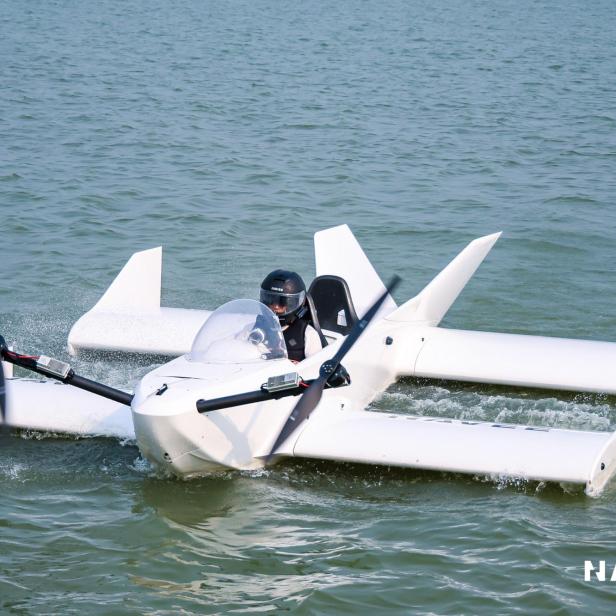 Kleines weißes Bodeneffektfahrzeug mit Propellern fährt auf dem Wasser, eine Person sitzt darin.