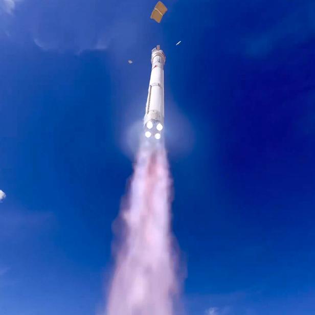 Eine Rakete startet senkrecht in den blauen Himmel und hinterlässt eine Rauchspur.