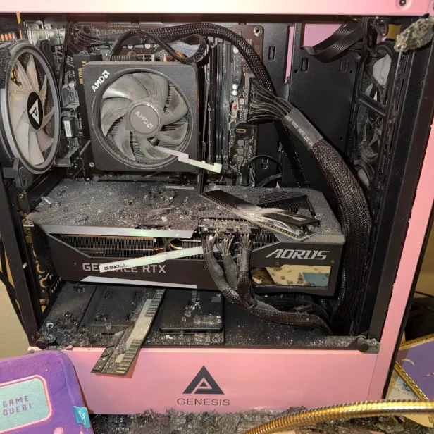 Zerstörter pinker Gaming-PC mit Glassplittern und beschädigten Komponenten auf einem Schreibtisch.