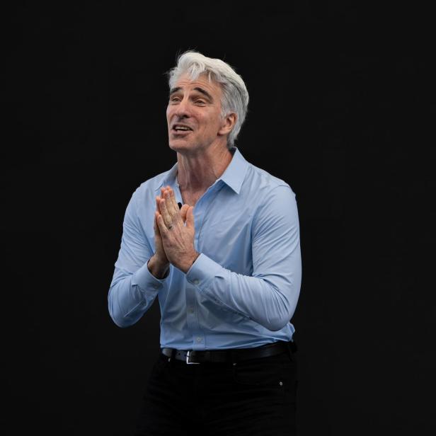 Craig Federighi steht vor einem schwarzen Hintergrund und hält seine Hände dankbar vor der Brust zusammen.
