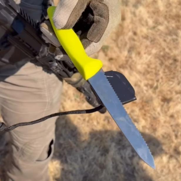 Ausschnitt aus einem Video zeigt einen Polizeibeamten, der ein Messer mit gelbem Griff in der Hand hält, das an einem Magneten hängt
