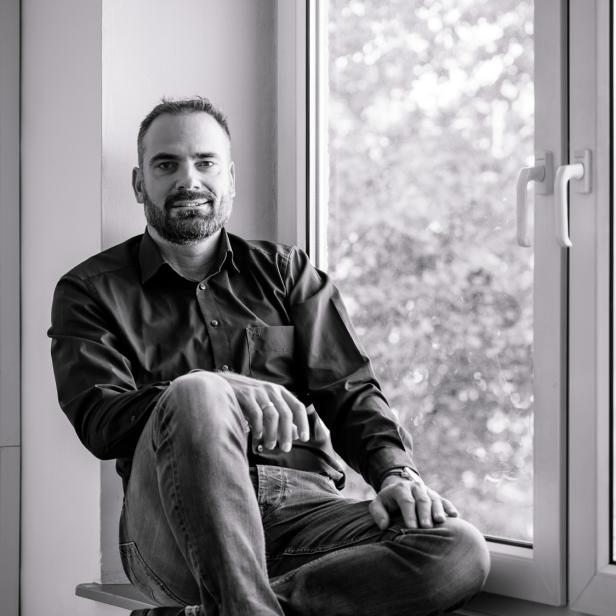 Ein Mann sitzt an einem Fenster; schwarz-weiß-Foto 