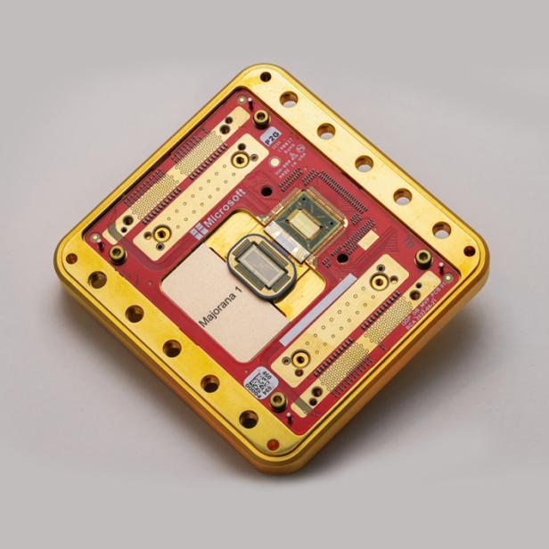 Microsofts Quantenchip Majorana 1 in einem goldenen Gehäuse auf grauem Hintergrund.