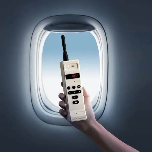 Hand hält ein Gerät mit Antenne vor einem Flugzeugfenster.