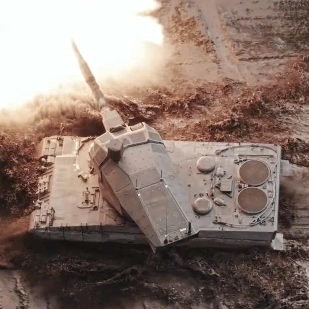 Kampfpanzer mit schlankem Turm feuert eine Kanone ab.