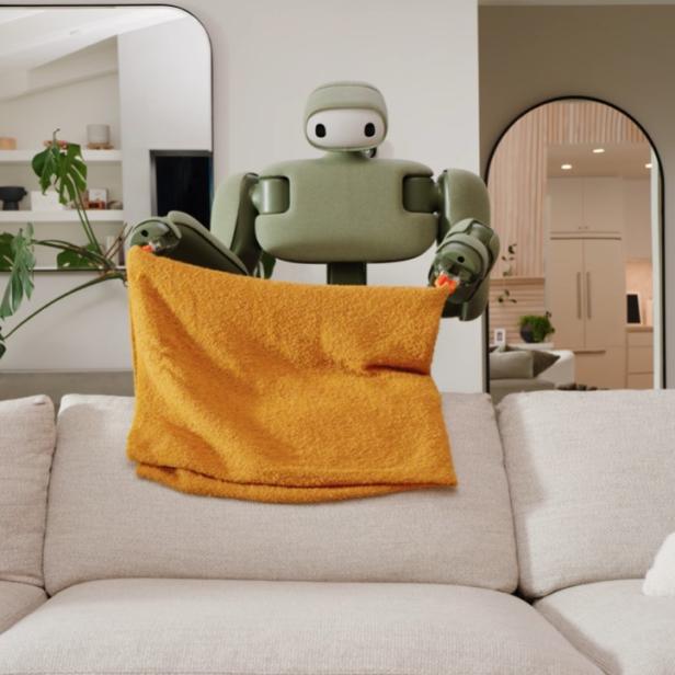 Roboter glättet ein Kissen auf einem Sofa.