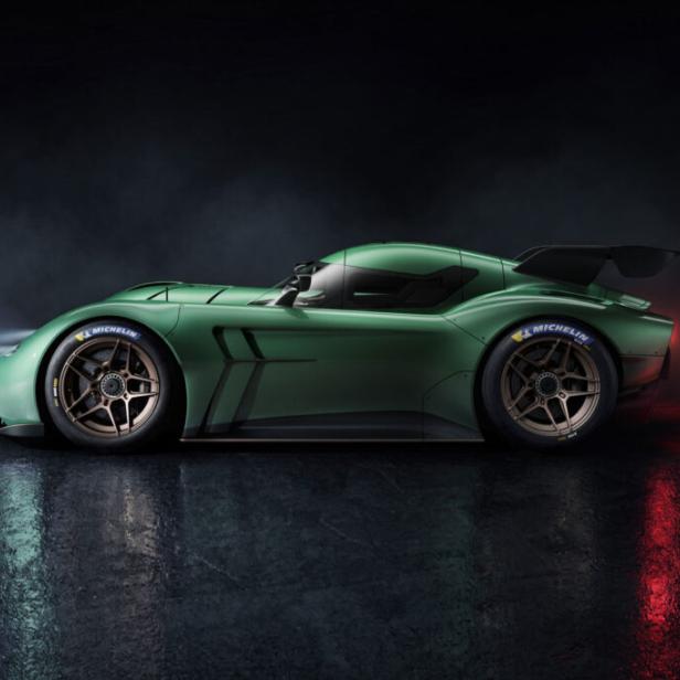 Grüner Rennwagen im Profil auf dunklem, nassem Untergrund mit reflektierenden Lichtern.