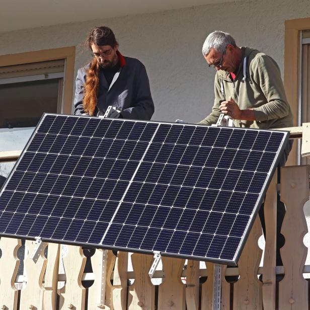 Two men assemble a balcony power plant to generate electricity