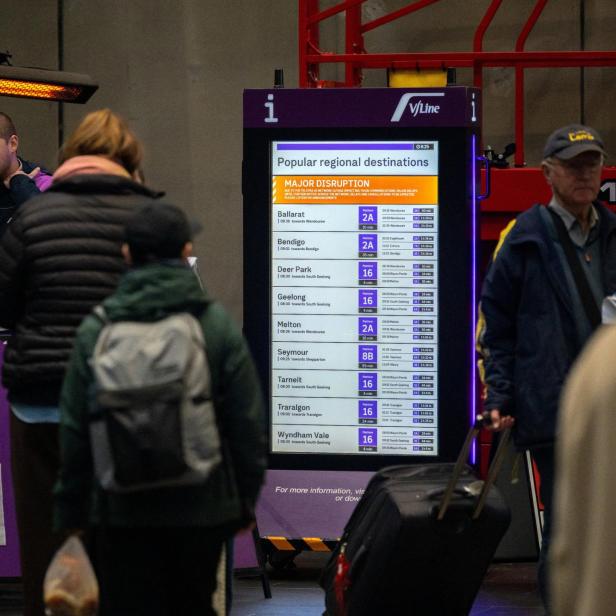 Bahnhofhalle mit V/Line-Informationsstand, Reisenden und Abfahrtsanzeige bei einer Störung.