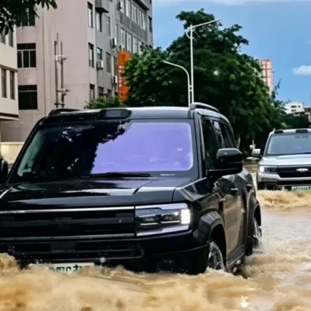 Zwei SUVs fahren durch überflutete Straße.