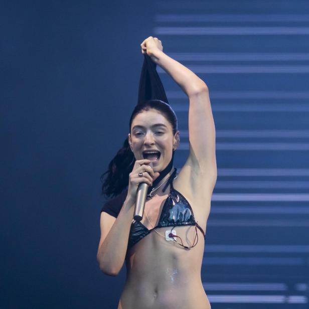 Die Sängerin Lorde singt auf einer Bühne in ein Mikrofon