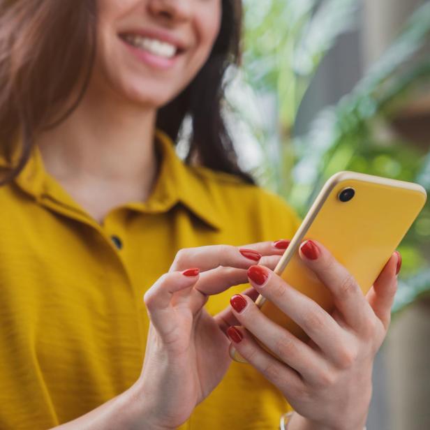Cropped image of happy girl using smartphone device while chilling at home