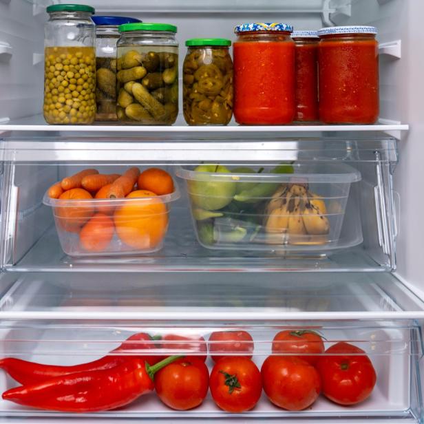 ein Kühlschrank voller Gläser, Gemüse und Obst, darunter Bananen und Tomaten