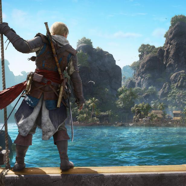 Edward Kenway steht auf dem Schiffsdeck und blickt auf eine tropische Inselbucht mit Felsen, Palmen und einem Dorf.
