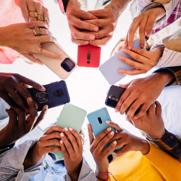Mehrere Personen halten ihre Smartphones in einem Kreis zusammen, wobei die Bildschirme nach innen gerichtet sind.