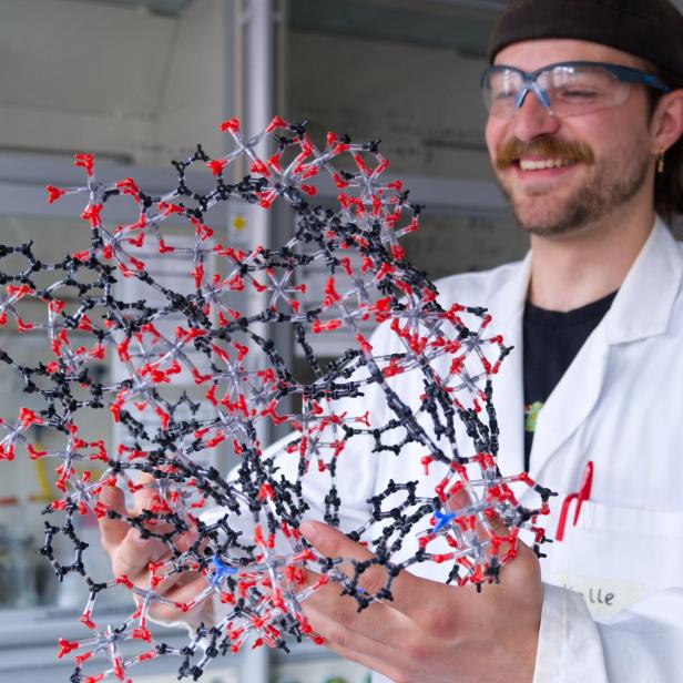 Kalle Mertin, Erstautor der Studie zur Maßstabsvergrößerung der Synthese von CAU-10-H, hält ein Modell einer Metall-organischen Gerüstverbindung (MOF) in den Händen.