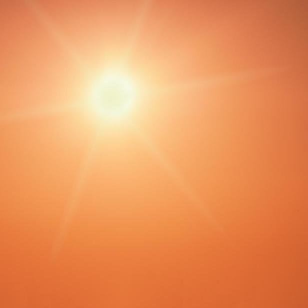 The sun shining brightly in a clear orange sky