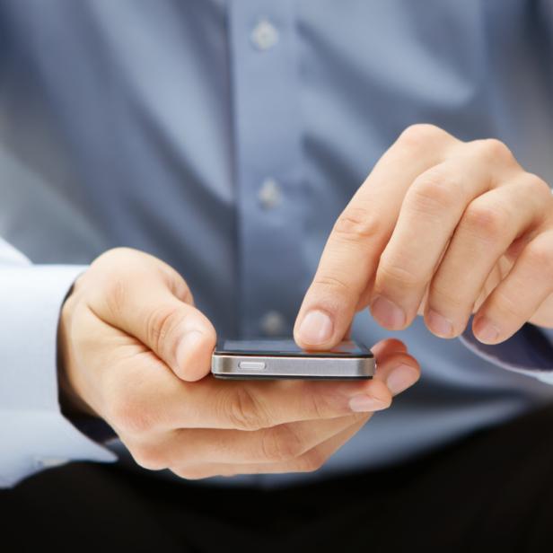Ein Mann im Hemd bedient ein Smartphone.