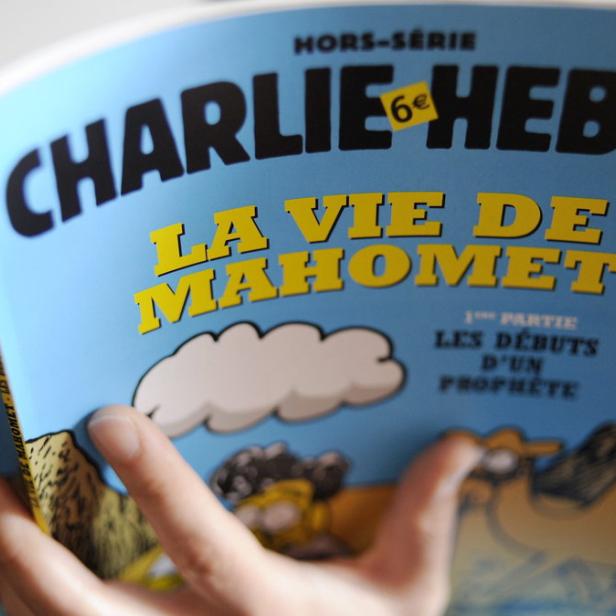 Eine Person liest eine Ausgabe von „Charlie Hebdo“ mit dem Titel „La Vie de Mahomet“.