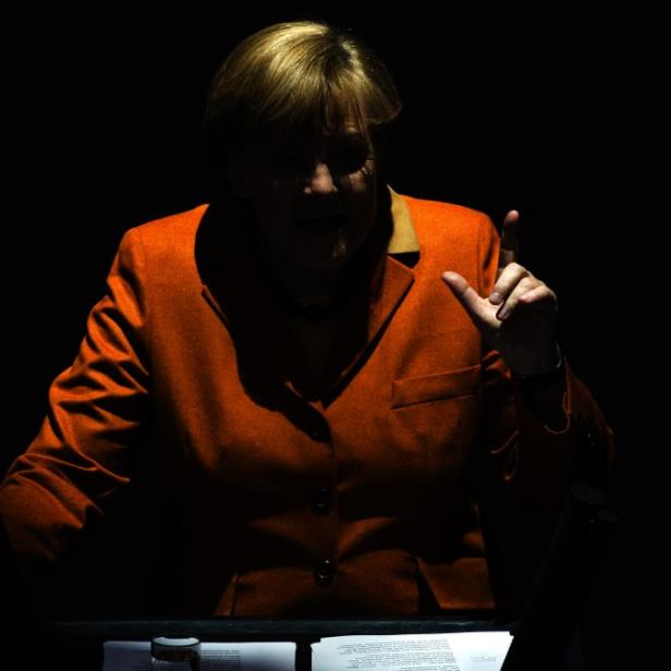 Angela Merkel gestikuliert während einer Rede im Dunkeln.